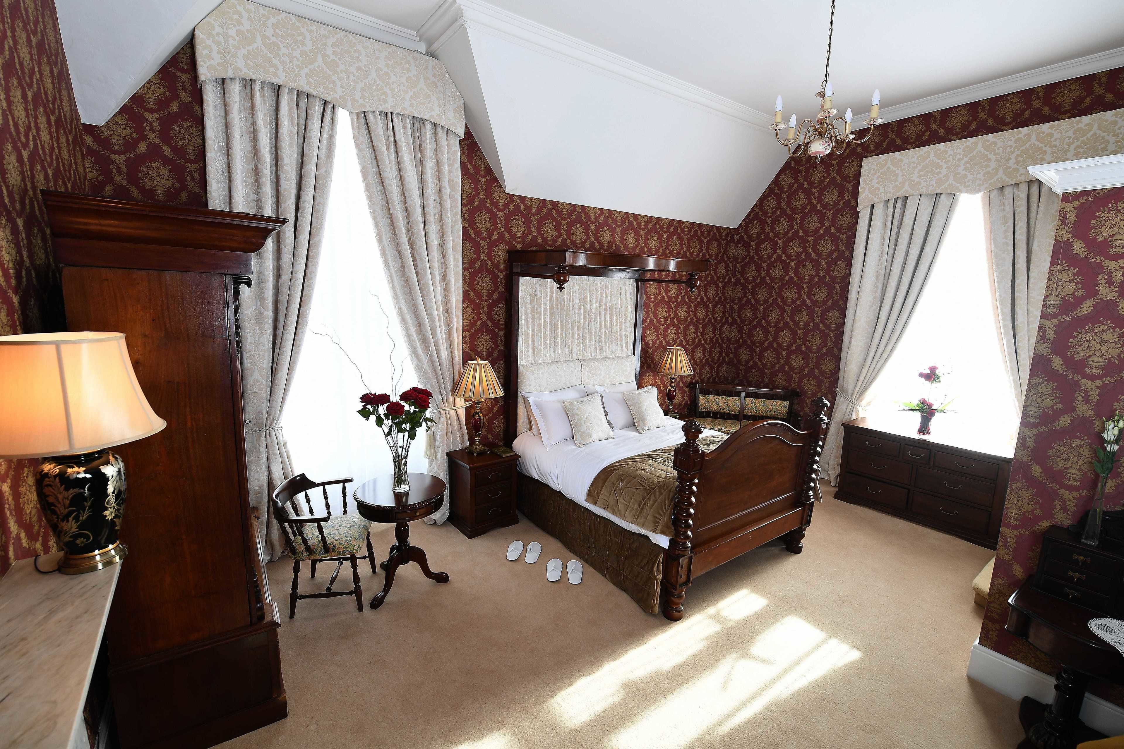 A bedroom with a large bed, a nightstand, a lamp, and a chair.