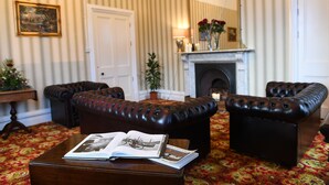 A room with striped wallpaper, a fireplace, leather sofas, and a book on a coffee table. - Glenduff Manor House (Tralee)