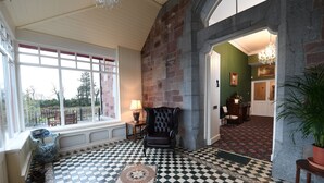 A room with a checkered floor, a large window, a chair, and a potted plant. - Glenduff Manor House (Tralee)