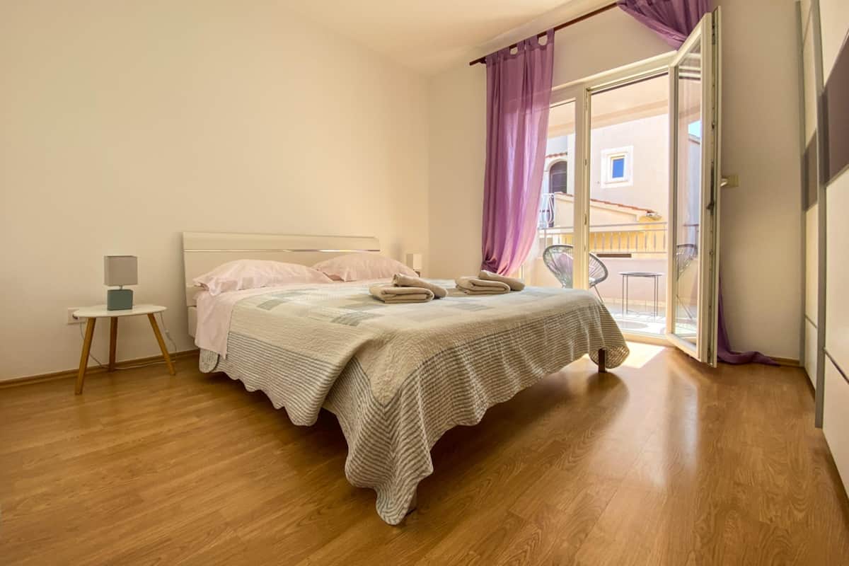 Un dormitorio con cama, una mesita de noche y vistas al balcón exterior.