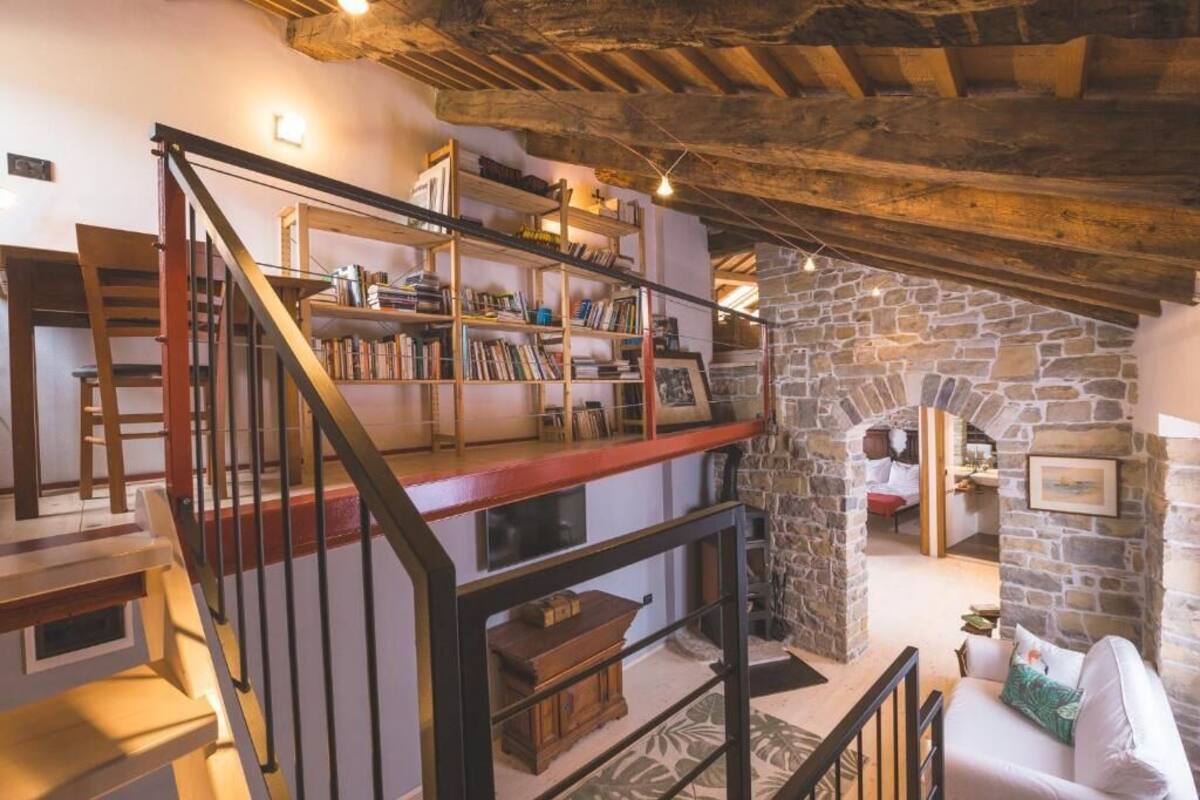 Un intérieur rustique avec un escalier en bois, des murs en pierre et un coin salon confortable.
