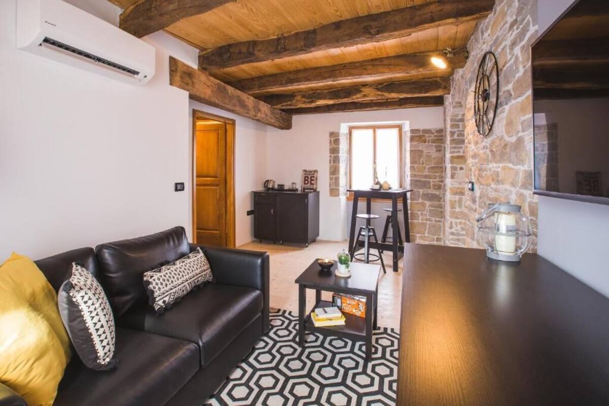 Un salon chaleureux avec un canapé en cuir noir, un tapis à motifs et un plafond en bois.