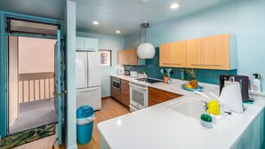 A modern kitchen with white appliances, wooden cabinets, and a blue accent wall.