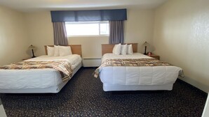 A hotel room with two beds, a window with curtains, a heater, and a clock on the nightstand.