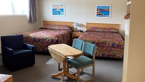 Une chambre d’hôtel avec deux lits, un bureau, une chaise et deux tableaux accrochés au mur.
