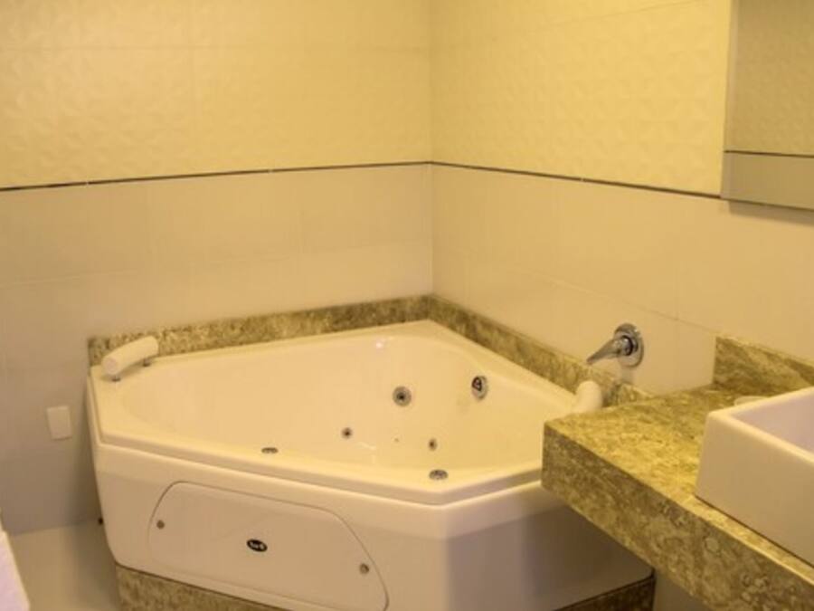 A bathroom with a white bathtub, a granite countertop, and a white sink.
