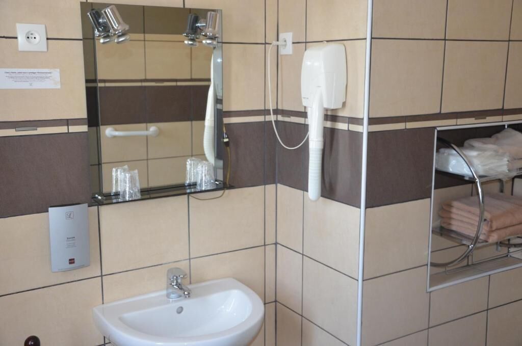 A bathroom with a sink, mirror, towel rack, and a hand dryer.