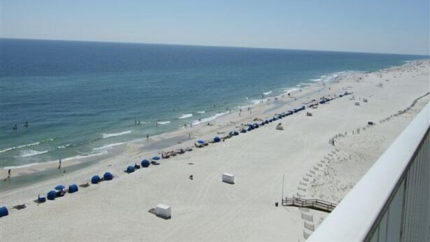 A beach with a long stretch of sand, a few umbrellas, and a clear sky. - Seawind 1008 by ALBVR (Gulf Shores)