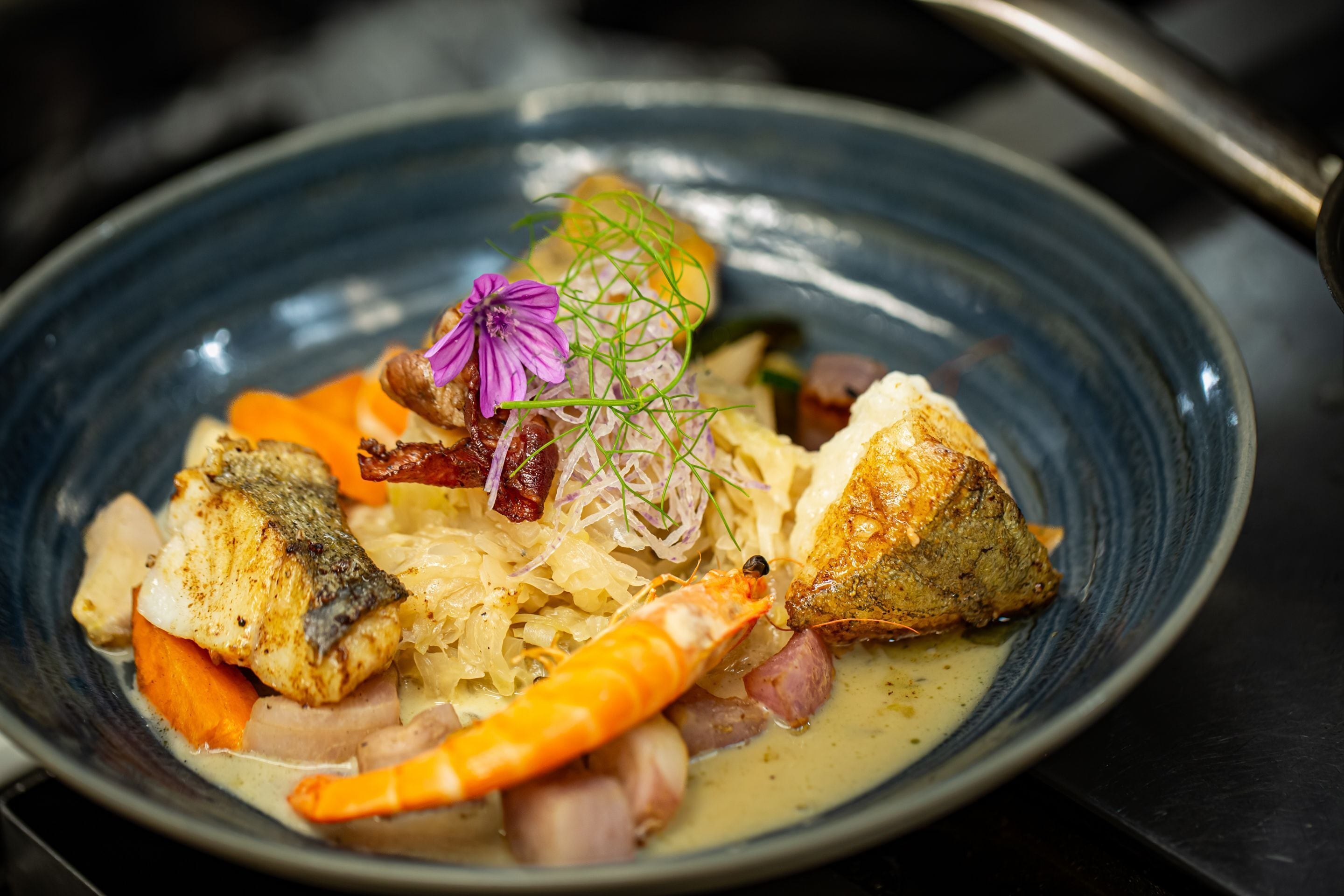 Een visgerecht met diverse ingrediënten en garnering op een bord.