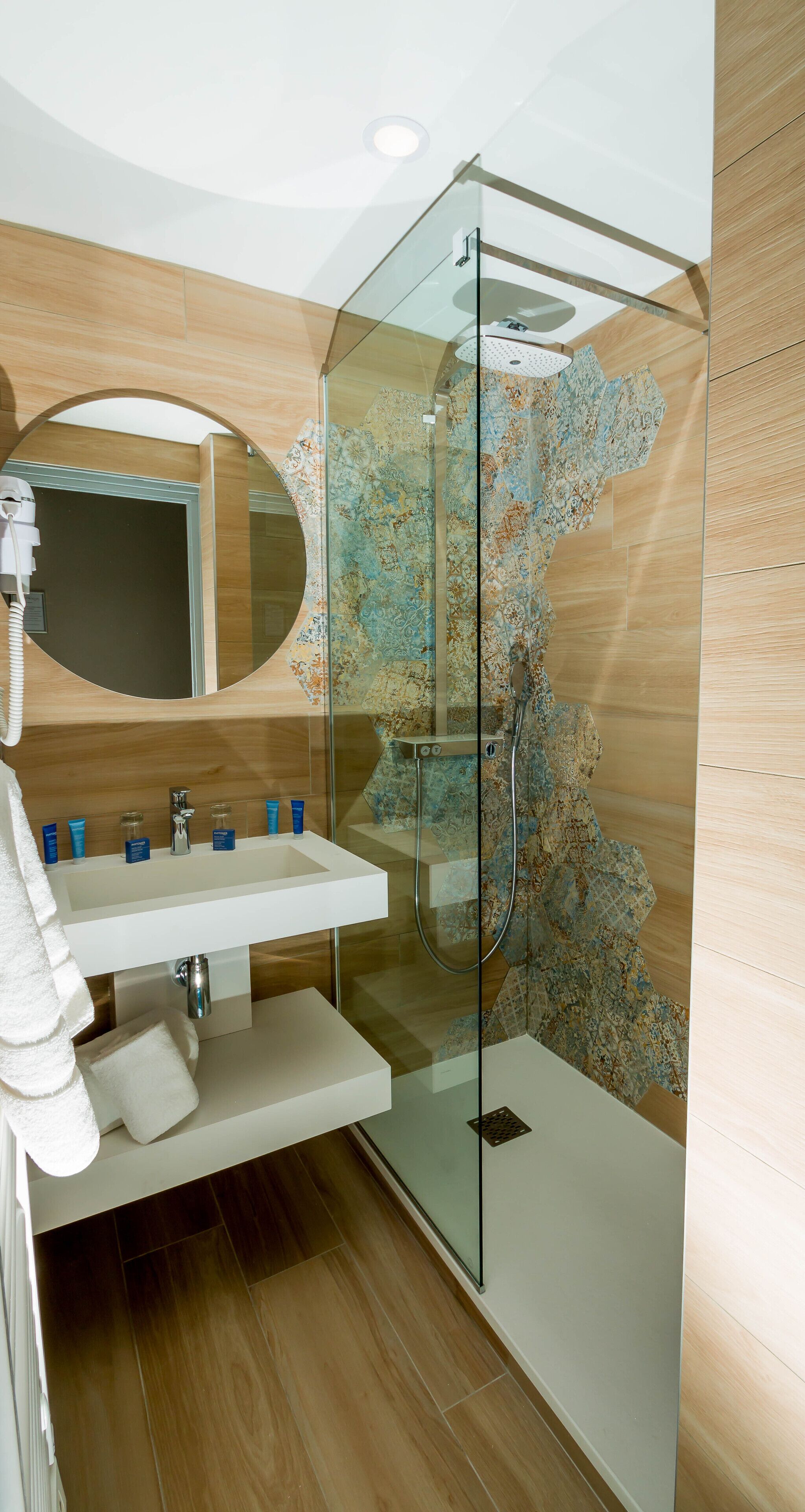 Une salle de bain moderne avec une douche à parois de verre, un lavabo blanc et un grand miroir.