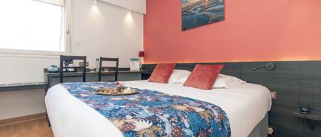 Een hotelkamer met een bed, een bureau, een stoel, een schilderij aan de muur en een raam.