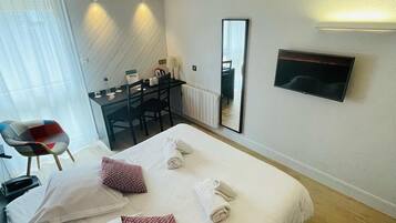 Une chambre d’hôtel avec deux lits, un bureau, une chaise, une télévision et une grande fenêtre avec des rideaux.