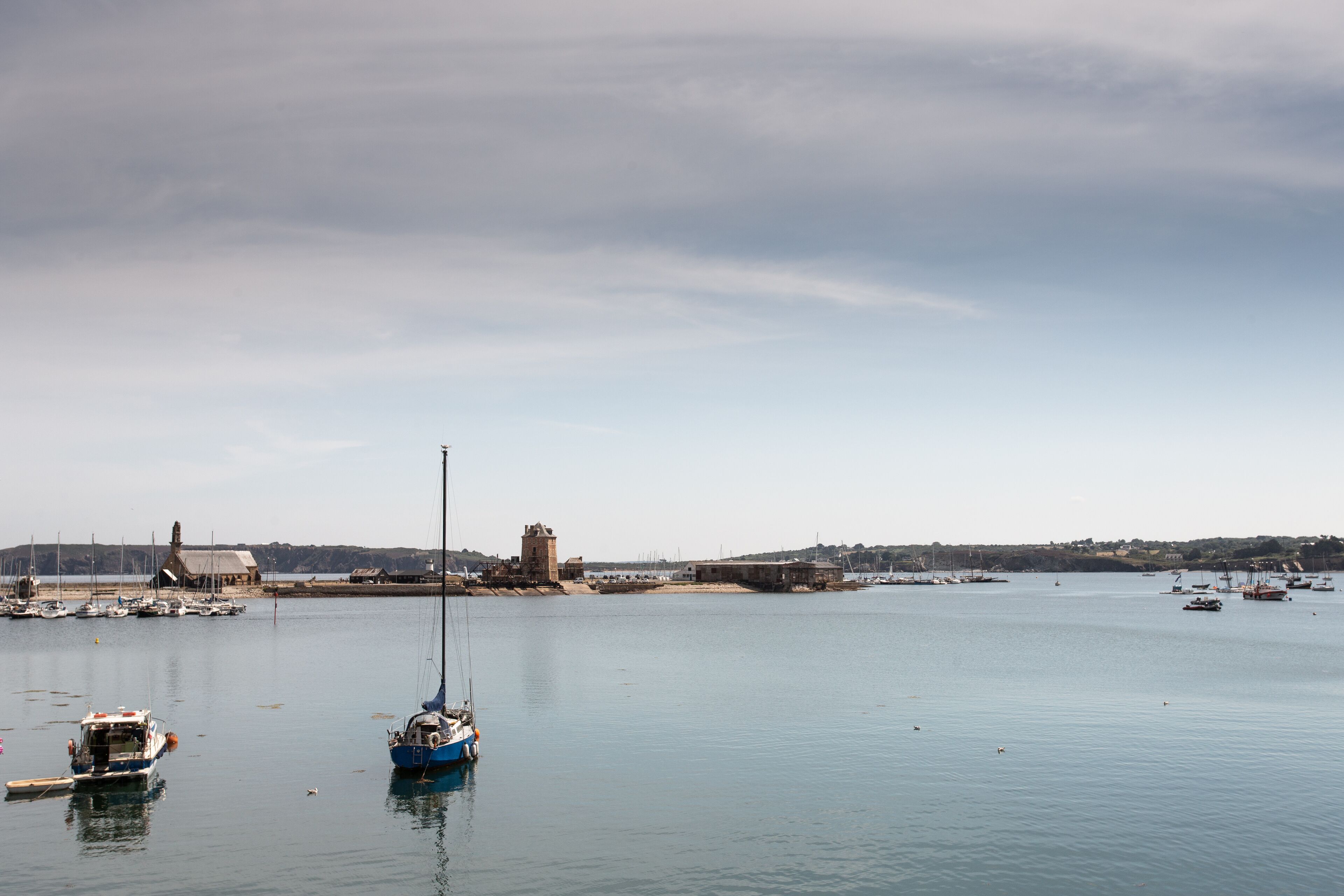 A harbor with boats, a lighthouse, and a historic tower.