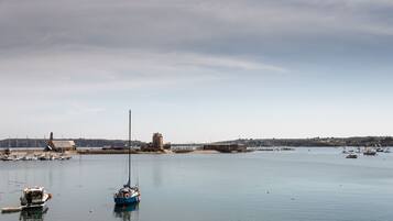 Un puerto con barcos, un faro y una torre histórica.