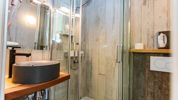 A modern bathroom with a glass-enclosed shower, a round sink, and a wooden vanity.