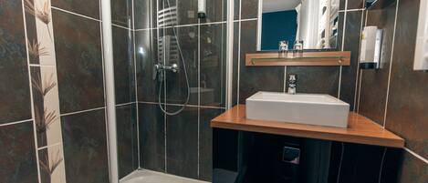 Une salle de bain moderne avec une douche à parois de verre, un lavabo blanc et un miroir au-dessus.