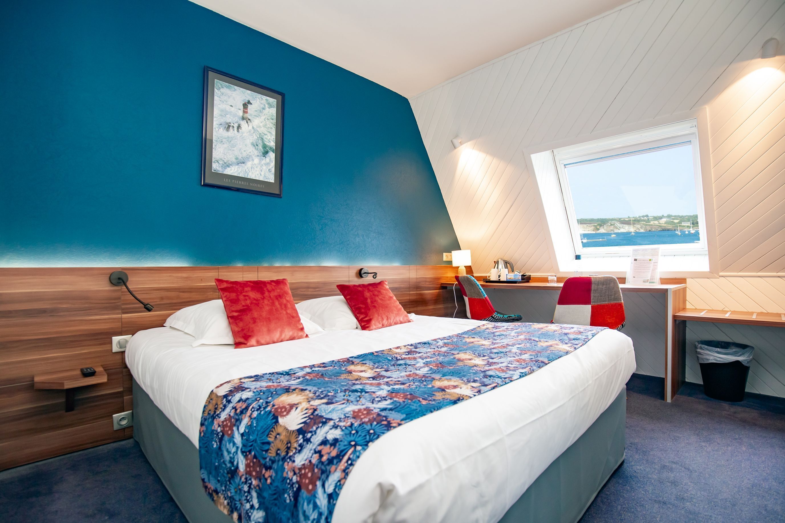 Habitación de hotel con una cama grande, un escritorio y una ventana con vista al mar.