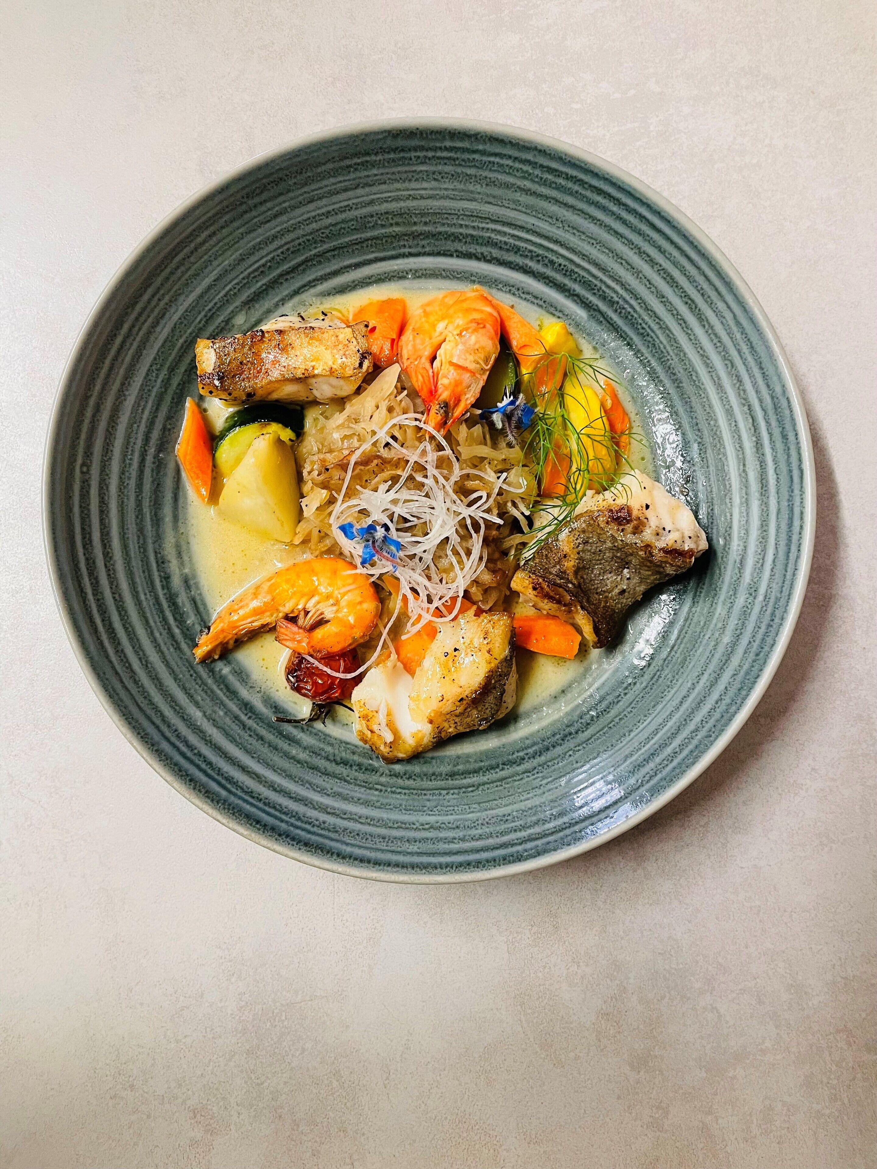 A plate of food with shrimp, fish, and vegetables.
