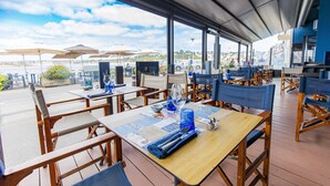 An outdoor dining area with tables and chairs, umbrellas, and a view of the water. - Logis Hôtel de France - Face à la Mer (Camaret-sur-Mer)
