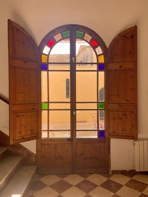 Een houten deur met glas-in-loodramen, leidend naar een trap.