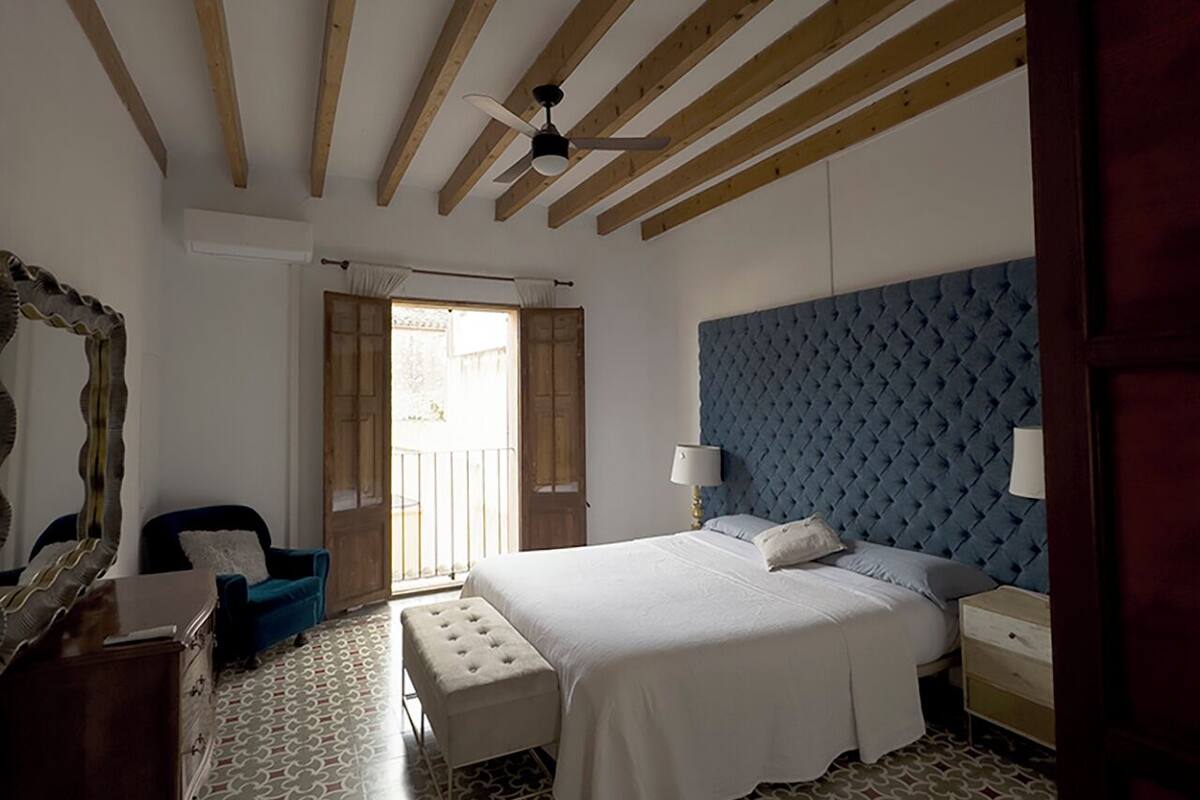 Une chambre à coucher comprenant un lit, une table de chevet, une chaise, une commode et un miroir.
