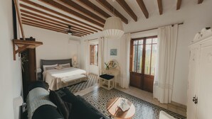 Quarto com cama, sofá, mesinha, espelho e janela com cortinas.