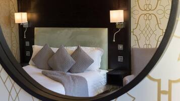 A bed with a headboard, two bedside lamps, and a mirror reflecting the room.