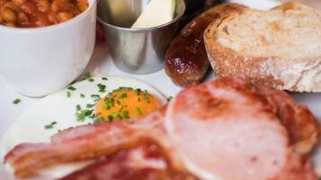 A breakfast plate with eggs, bacon, sausages, toast, and baked beans.