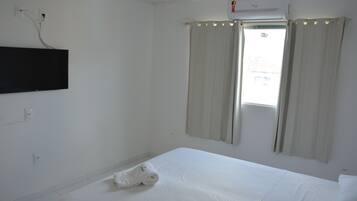 Una habitación de hotel con una cama, un televisor de pantalla plana en la pared y una ventana con cortinas.