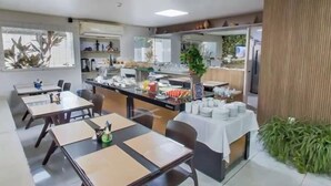Un comedor con mesas, sillas y una disposición tipo bufé.