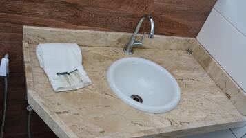 Un baño con lavamanos de mármol, una toalla y un cabezal de ducha.