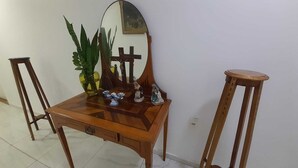 A wooden table with a mirror, a potted plant, and a small statue. - Goyanna Hotel (Goiana)