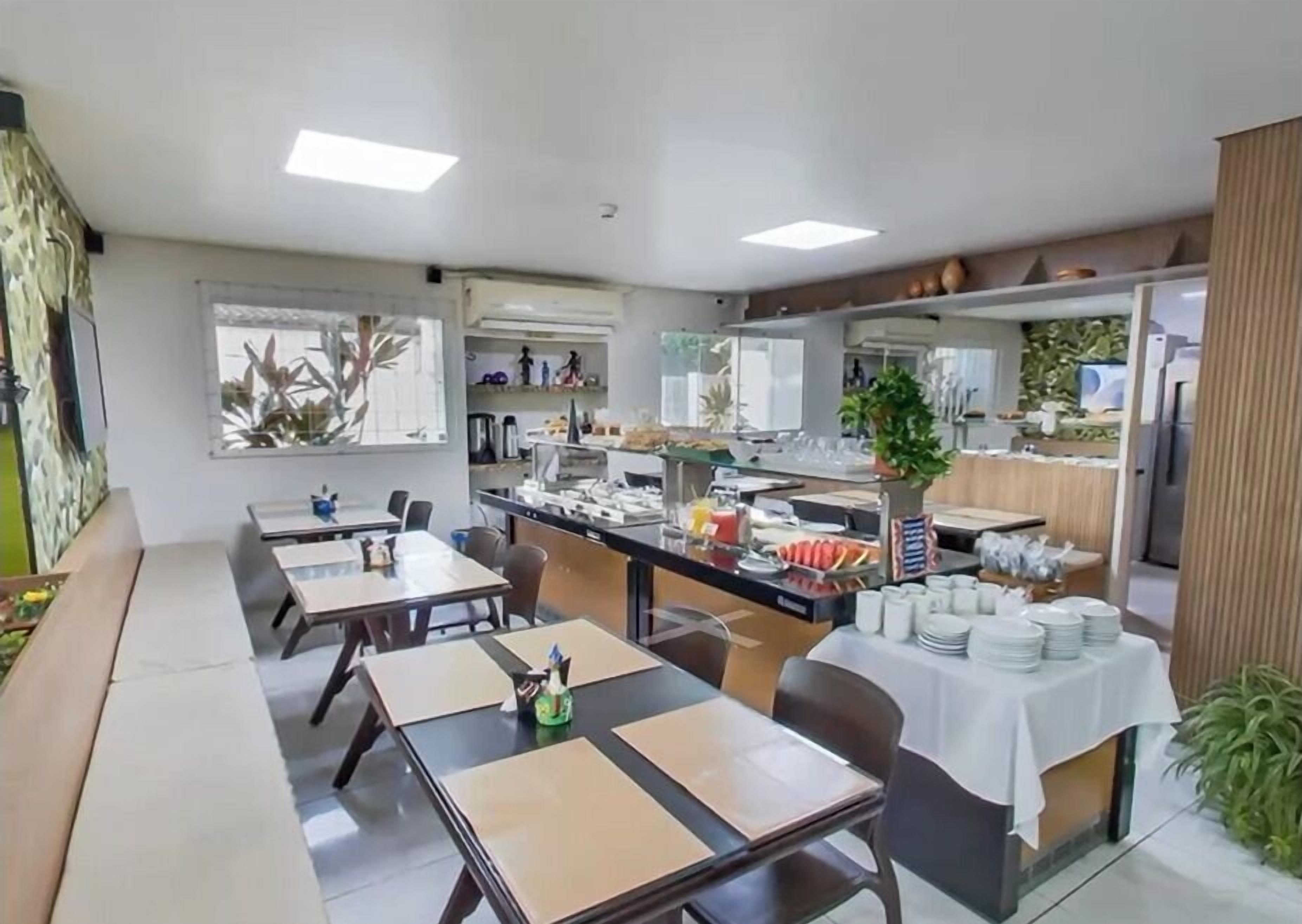 A dining area with tables and chairs, a buffet counter, and a kitchen in the background.