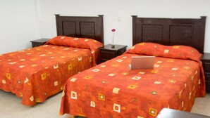 Two single beds with matching headboards and footboards, a bedside table with a laptop, and a vase with a single flower on the nightstand. - Hotel Zirahuen (Lazaro Cardenas)