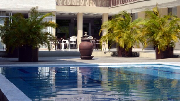 A pool area with palm trees and outdoor seating. - Hotel Zirahuen (Lazaro Cardenas)