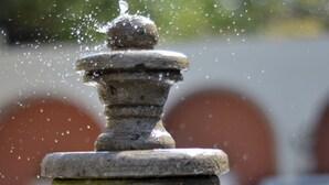 A stone fountain with water spouting from the top, set against a blurred background. - Hotel Zirahuen (Lazaro Cardenas)