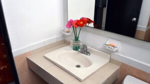 A bathroom with a white sink, a mirror above it, and a toilet. - Hotel Zirahuen (Lazaro Cardenas)