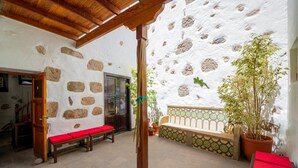 A courtyard with stone walls, a wooden bench, a potted plant, and a tiled bench area. - Hotel Rural Villa de Agüimes (Aguimes)