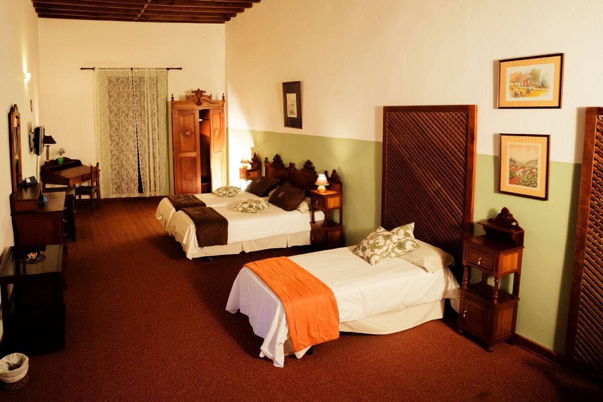 A hotel room with two beds, a desk, a chair, and a wardrobe.