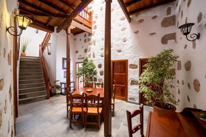 A rustic interior with a stone wall, wooden staircase, and a dining area with a table and chairs. - Hotel Rural Villa de Agüimes (Aguimes)