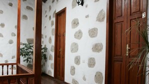 A hallway with white stucco walls, wooden doors, and a wooden staircase. - Hotel Rural Villa de Agüimes (Aguimes)