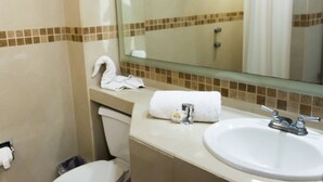 Un baño con lavamanos, espejo y toallero.
