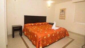Habitación de hotel con una cama individual, una mesita de noche, una lámpara fijada en la pared y un certificado en un marco colgado.