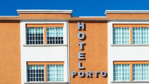 Un hotel con un letrero que dice "HOTEL PORTO" y varias ventanas con marcos blancos y detalles naranja.
