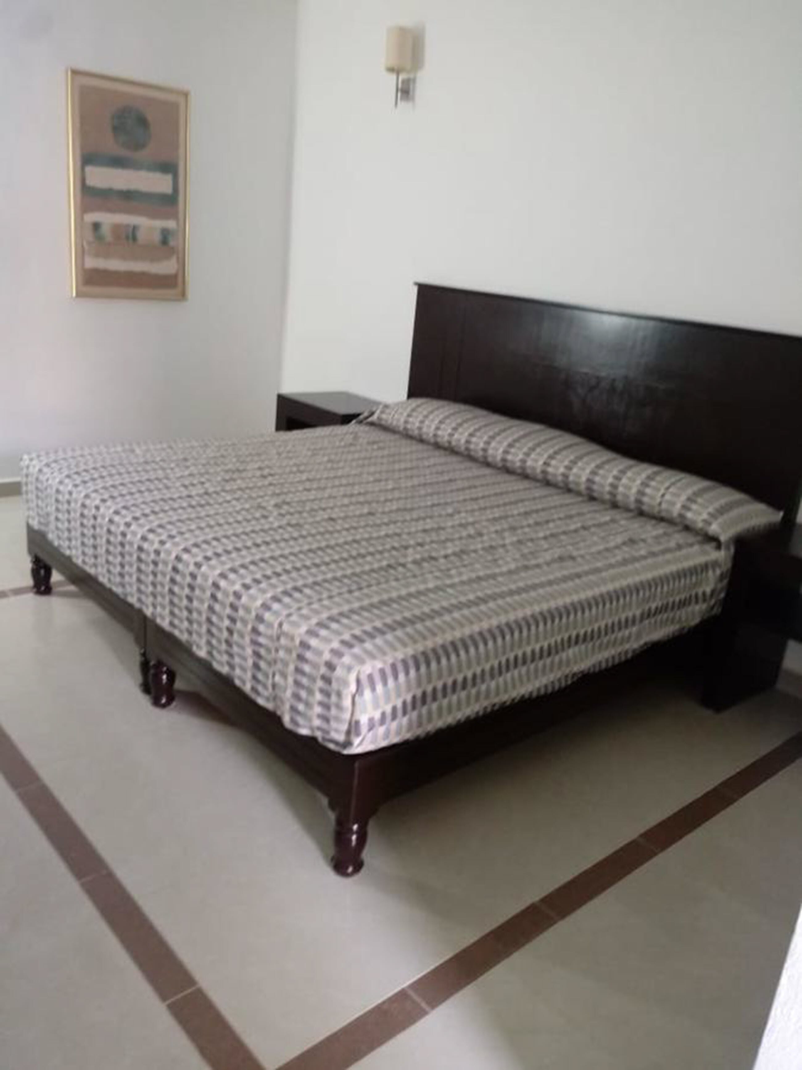 A bedroom with a bed, nightstands, and a wall-mounted light fixture.