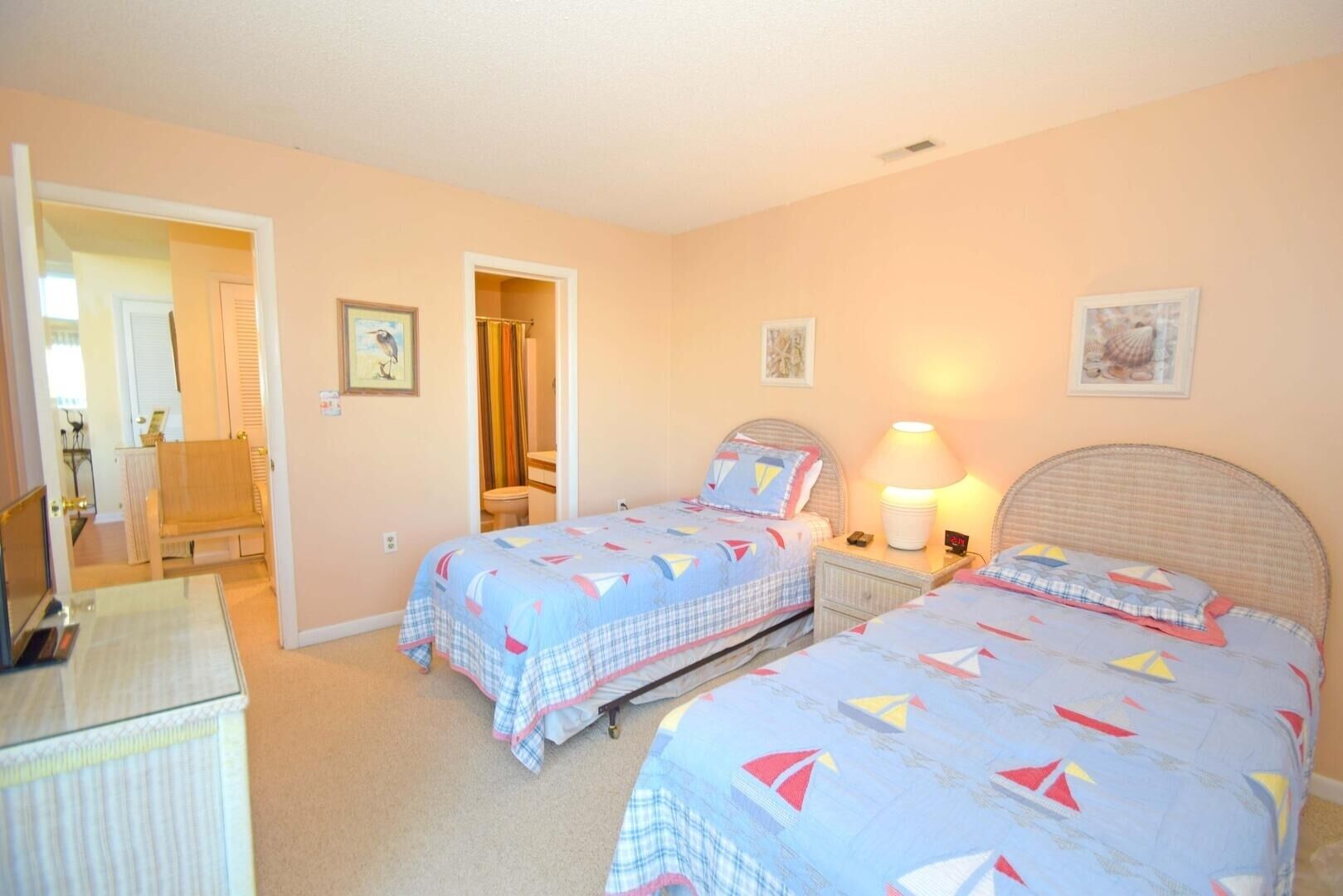 A bedroom with two beds, a desk, and a chair. There are doors leading to other rooms.