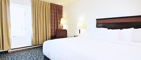 A hotel room with a large bed, two bedside lamps, a chair, and a window with curtains.