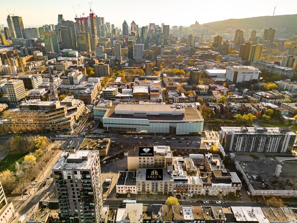 A cityscape with a prominent modern building with a glass facade and a large parking lot in the foreground. - Lelux Hotel (Montreal)