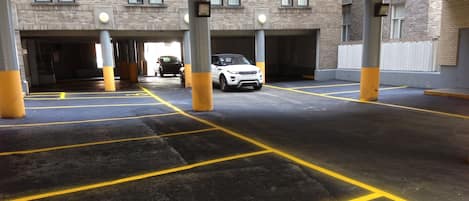 A parking garage with marked parking spaces and a white car parked in one of the spaces.