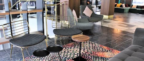 A modern lounge area with a sofa, chairs, a coffee table, and a patterned rug.